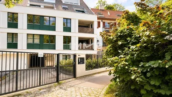 Modernes Mehrfamilienhaus mit weißer Fassade, grünen Fensterrahmen und Einfahrtstor.