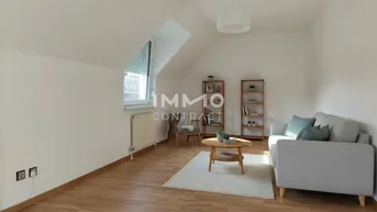 Helles Wohnzimmer im Dachgeschoss mit Schrägdecke, Holzfußboden und modernem Sofa.