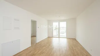 Lichtdurchfluteter Raum mit Holzparkett und Zugang zu einem französischen Balkon.