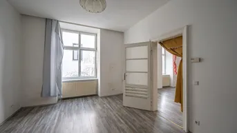 Helles, leeres Zimmer mit Laminatboden und großem Fenster, bereit zur individuellen Gestaltung.