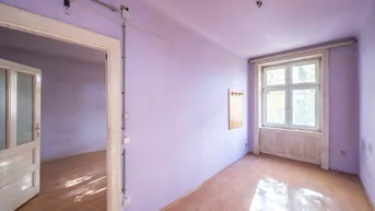 Geräumiger Raum mit hellvioletten Wänden, Holzfußboden und großem Fenster, bereit zur Renovierung.