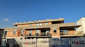 Rohbaufertigstellung eines modernen Gebäudes mit mehreren Etagen und großen Fensteröffnungen unter blauem Himmel.