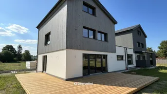 Neubau-Doppelhaushälfte mit moderner Holzfassade und großer Holzterrasse im Garten.
