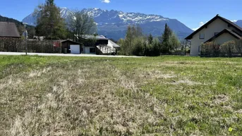 Weitläufiges Grundstück mit grüner Wiese und beeindruckendem Bergblick unter blauem Himmel.