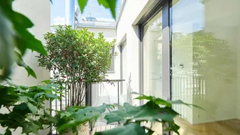 Heller Balkon mit Topfpflanzen und Blick auf die moderne Gebäudefassade.