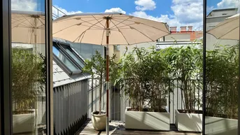Sonnige Terrasse mit Holzboden, großen Pflanzenkübeln und einem Sonnenschirm für entspannte Stunden im Freien.