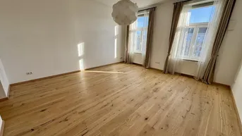 Sonniges Zimmer mit hellem Holzparkettboden und großen Fenstern, die viel Tageslicht hereinlassen.
