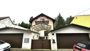 Vorderansicht des Hauses mit zwei Garagen und überdachtem Eingangsbereich.
