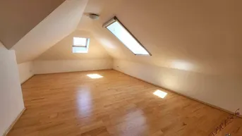 Helles Dachzimmer mit Holzboden und Dachfenstern, ideal als Schlaf- oder Kinderzimmer.