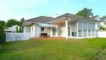 Großer Gartenbereich hinter dem Haus mit Rasenfläche, Terrasse und Markise für Schatten.