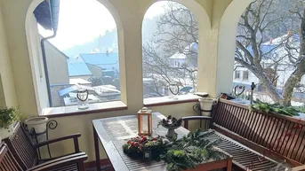 Überdachte Loggia mit Holztisch und Bänken, ideal für Mahlzeiten im Freien.