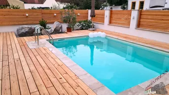 Gepflegter Außenbereich mit privatem Pool, Holzdeck und Sichtschutz aus Holz.