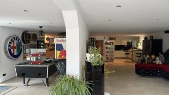 Geräumiger offener Wohnbereich mit Billardtisch, Bar und Blick auf die moderne Küche.