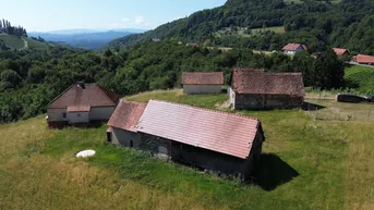 Luftaufnahme eines ländlichen Anwesens mit mehreren Gebäuden und Weinbergen in hügeliger Landschaft.