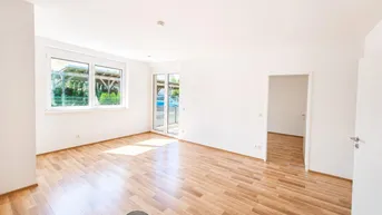 Helles Wohnzimmer mit Laminatboden, großen Fenstern und Zugang zu einem Außenbereich.