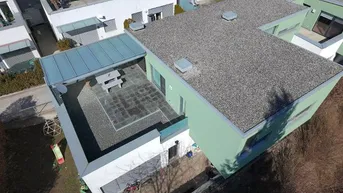 Luftaufnahme eines modernen Hauses mit großer, überdachter Terrasse und angrenzendem Gartenbereich.