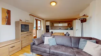 Gemütlicher Wohnbereich mit Sofa und offener Küche in modernem Design.