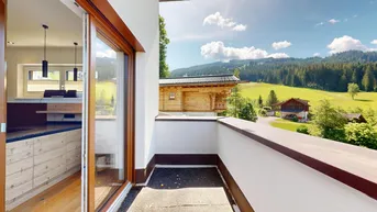Heller Balkon mit Holzboden und weitem Blick auf die grüne Berglandschaft.