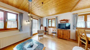 Gemütliches Wohnzimmer mit Holzbalkendecke, hellem Parkettboden und traditionellen Möbeln.