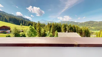 Panoramablick auf die umliegende Berglandschaft und grüne Wälder.