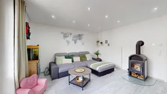 Gemütliches Wohnzimmer mit modernem Sofa, Holzboden und einem stilvollen Kaminofen.