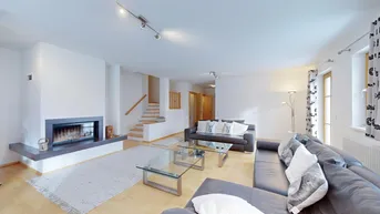 Helles Wohnzimmer mit modernem Kamin, bequemen Sofas und Zugang zu einer Treppe.
