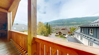 Geräumiger Holzbalkon mit weitem Blick auf die umliegende Berglandschaft.