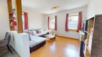 Helles Wohnzimmer mit Laminatboden, bequemer Couch und dekorativen Elementen.