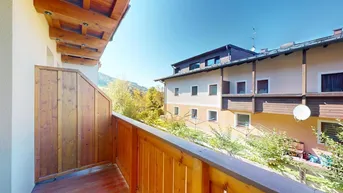 Geräumiger Holzbalkon mit Bergblick und Blick auf die umliegenden Gebäude.