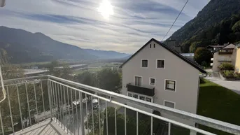 Balkon mit weitem Blick auf die umliegende Berglandschaft und andere Gebäude.