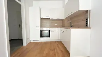 Moderne Einbauküche in Weiß mit Holzdetails, ausgestattet mit Backofen und Kochfeld, ideal für den Erstbezug.