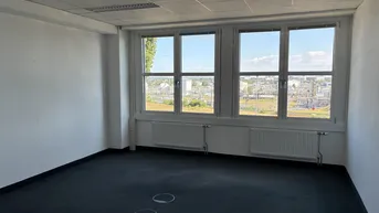Geräumiges Büro mit großen Fenstern, die einen weiten Blick auf die Umgebung bieten und viel Tageslicht hereinlassen.