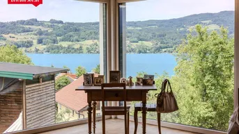Helles Arbeitszimmer mit großen Fenstern und atemberaubendem Blick auf den See und die umliegende Landschaft.