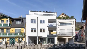 Modernes Mehrfamilienhaus mit Balkonen und Solaranlage in städtischer Umgebung.