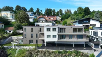 Modernes Apartmentgebäude im Sommer mit grüner Umgebung und großzügigen Balkonen.