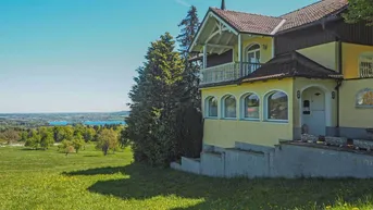 Gelbes Haus mit traditioneller Architektur und weitem Blick auf die Landschaft und einen See.