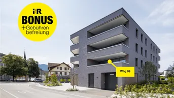 Modernes Mehrfamilienhaus mit grauer Fassade, Balkonen und Blick auf die umliegende Stadt und Berge.