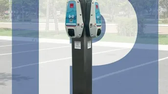 Moderne Ladestation für Elektrofahrzeuge auf einem Parkplatz, umgeben von Bäumen.