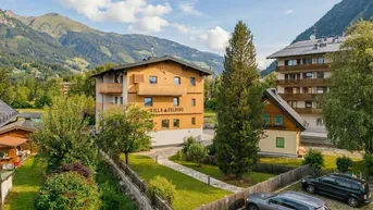 Modernes Gebäude mit Holzfassade und Balkonen in einer malerischen Berglandschaft.