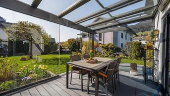 Heller Wintergarten mit Glasdach und Blick auf den gepflegten Garten, ideal für entspannte Stunden im Freien.