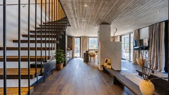 Modernes Interieur mit Holzfußboden, offener Treppe und Blick auf die Berge.