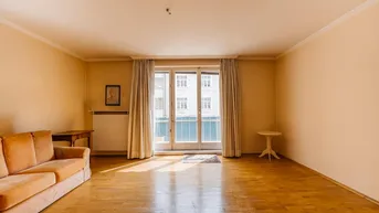 Geräumiges Wohnzimmer mit Holzparkett und Zugang zu einem französischen Balkon.