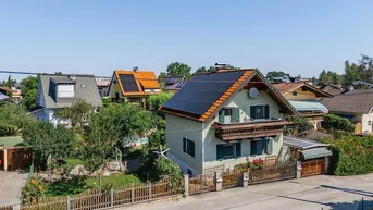 Luftaufnahme eines Wohnhauses mit Solaranlage und umliegenden Gärten in einer Siedlung.