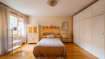 Helles Schlafzimmer mit Holzboden, Einbauschränken und klassischer Einrichtung, die eine gemütliche Atmosphäre schafft.