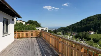 Geräumige Holzterrasse mit Geländer und Panoramablick auf die bewaldeten Hügel und die Stadt in der Ferne.
