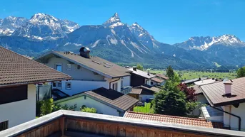 Panoramablick über eine Siedlung mit traditionellen Häusern und majestätischen schneebedeckten Bergen im Hintergrund.