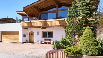 Modernes Holzhaus mit weißer Fassade, großer Garage und gepflegter Auffahrt.