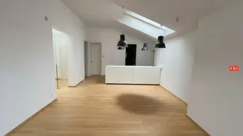 Heller, offener Wohnbereich mit Holzboden, Dachfenster und moderner Beleuchtung.