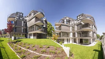 Moderne Wohngebäude mit geschwungenen Balkonen und großen Fenstern, umgeben von gepflegten Grünflächen und Gärten.