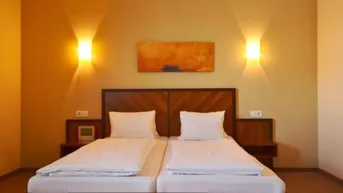 Gemütliches Schlafzimmer mit zwei Einzelbetten, Holzkopfteil und warmem Licht für eine angenehme Atmosphäre.